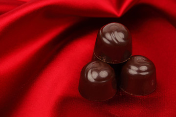 Wall Mural - chocolate candy on red satin