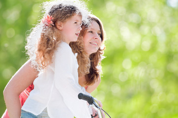 Poster - young mother and her daughter on bicycle