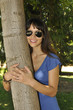 Mujer joven con gafas de sol abrazada a un árbol