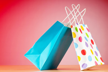 Colourful paper shopping bags against gradient background