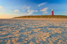 Seaside With Sand Dunes And Lighthouse At Sunset