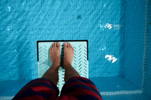 Feet On Diving Board Over Pool