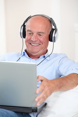Wall Mural - Senior man listening to music with headphones