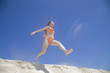 砂浜の砂を蹴る水着女性
