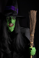 Wicked witch with her broom stick, black background.