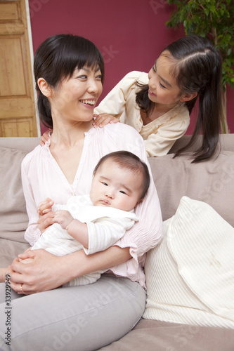 赤ちゃんを抱っこする母親の肩に手を置く娘 Stock Photo Adobe Stock