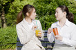 © paylessimages - 公園のベンチで飲み物を飲む2人の女性