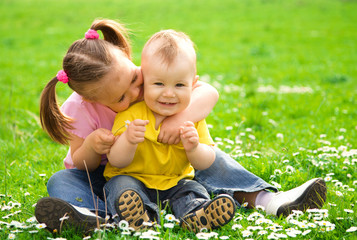 Wall Mural - Two children are sitting on green meadow