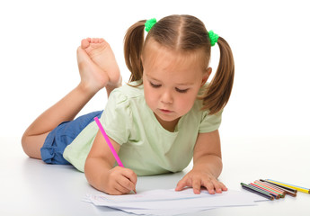 Little girl is drawing while laying on the floor