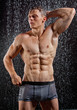 Wet muscle sexy young man posing under the rain in studio