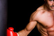 © cristovao31 - Athletic young boxer fighter punching bag over black background