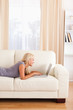 © WavebreakmediaMicro - Portrait of a woman lying on a couch using a notebook
