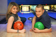 © Pavel Losevsky - Couple lie on parquet leaning against and hold balls for bowling