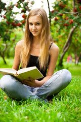 Beautiful female student outdoors with a book at campus park