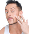 Handsome man applying male creme on face