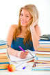 © Alliance - Smiling teen girl sitting at table with lots of books