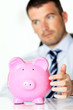 © Frédéric Prochasson - young man with pink piggy bank in office