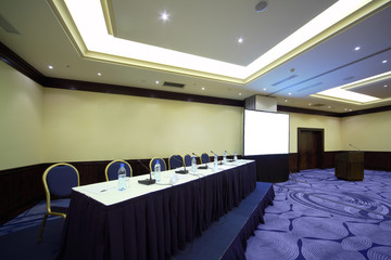Wall Mural - Big table with microphone near screen in bright conference hall