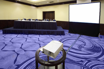 Wall Mural - Big table with microphone near screen in bright conference hall,