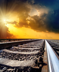 Wall Mural - railway to horizon under dramatic sky with sun