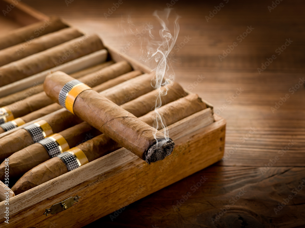 smoking cuban cigar over box  on wood background - obrazy, fototapety, plakaty 