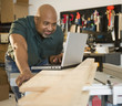 © JGI/Jamie Grill/Blend Images - African American carpenter using laptop in workshop