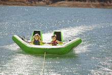 Children Riding Inflatable Raft On Lake