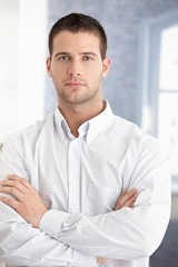 Canvas Print - Young businessman standing arms crossed