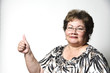 a 60 year old Hispanic woman showing the thumbs up hand sign.