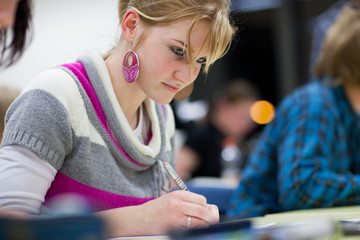 Wall Mural - pretty female college student sitting in a classroom