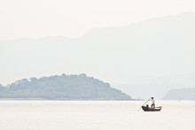 A Fisherman On Boat Alone In The Sea, Low Saturation Picture.