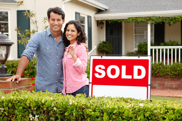 Canvas Print - Hispanic couple outside home with sold sign