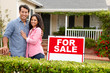 © Monkey Business - Hispanic couple outside home with for sale sign