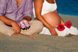 Pareja esperando un bebé sentada en la playa