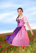 Young woman with dirndl dress in poppy field