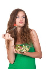 Wall Mural - Portrait of young thinking woman eating vegetable salad