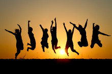Silhouette Of Friends Jumping In Sunset
