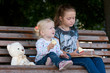© Sergii Mostovyi - two sisters sitting  on a bench at the park.