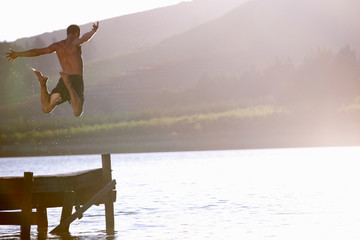 Young man jumping into lake