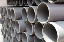 Gray PVC Tubes Plastic Pipes Stacked In Rows