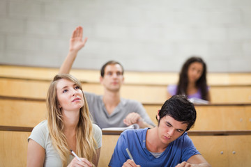 Poster - Students taking notes while their classmate is raising his hand