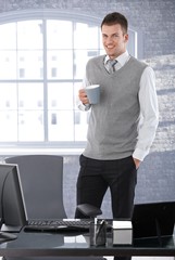 Wall Mural - Casual businessman drinking tea in office smiling