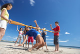 Fototapeta  - Teenagers doing limbo dance on beach