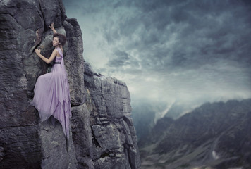 Conceptual photo of a woman climbing to the top of a mountain