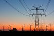 Strommast bei Sonnenuntergang mit Windrädern und Kernkraftwerk