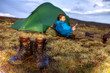 Wanderschuhe mit Zelt und Wanderer im Hintergrund