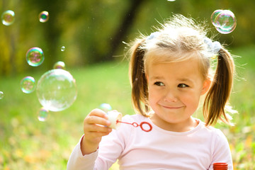 Wall Mural - Little girl is blowing a soap bubbles