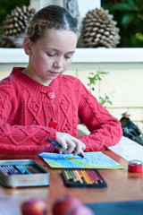 young girl in red knit sweater drawing picture