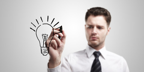 Poster - Business man drawing a light bulb on a glass screen