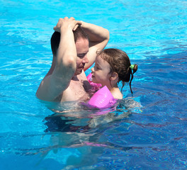 Joyful little girl with dad in the pool